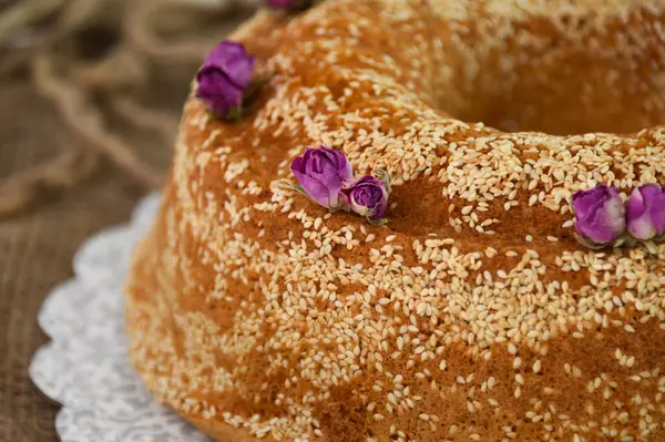 Zarif lavantalı kek, pudra şekerle hafifçe tozlanmış ve üzerine beyaz jöle serpiştirilmiş ve susam tohumları serpiştirilmiş fırınlanmış kafe tatlısının yakın görüntüsü.