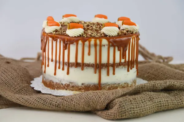 Krem peynirli havuçlu kek ve karamel karamel soslu ezilmiş fındıklı ve peçete tarafından izole edilmiş klasik lezzetli pasta.