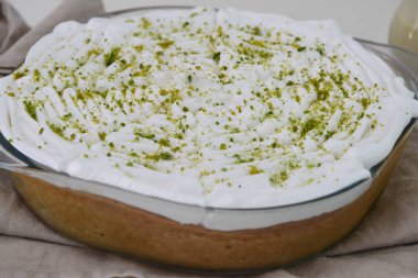 Limonlu turta şeffaf bir cam kabın içinde üzerine krema serpilmiş parlak yeşil limon tadı ve küçük süt sosu şişesi serinletici sütün üst görüntüsünde izole edilmiş.