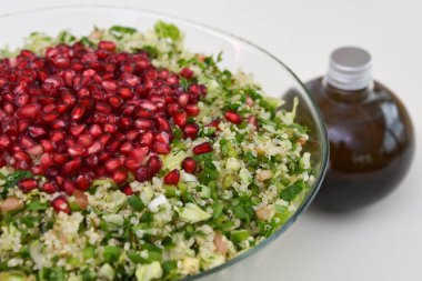 Nar tohumları, doğranmış maydanoz, bulgur, domates ve zeytinyağı şişeli naneli taze Tabbouleh salatası.