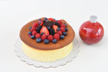 Üzerinde çilek, ahududu, böğürtlen ve kırmızı böğürtlen sosu olan yumuşak Japon cheesecake 'i.