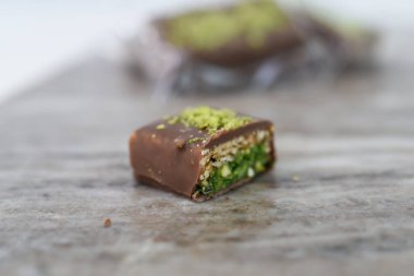 Çürük Çukulatalı Pistachio çikolatası Wafer katmanları ile ikiye bölünmüş. Çikolata tabakası, ince çıtır gofret katmanları ve tatlı tatlı tatlıyı dolduran şam fıstığı manzarası sergileniyor.