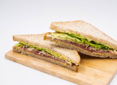 Klasik Tütsülenmiş Biftek Pastırması ve Marullu Buğday Sandviçi. Tahta pano tarafında öğle yemeği menüleri.