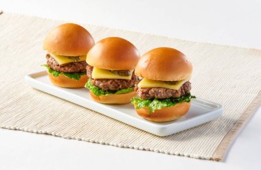 Her biri sulu bir köfte, erimiş peynir, kıtır marul ve turşu dilimli ve restoran menülerinde servis edilen Amerikan Angus bifteği veya Mini çizburgerler.