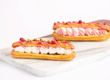 Kremalı gurme Pembe Eclairs, Pistachios ve kurutulmuş ahududu mermer pano manzaralı tatlı menüleri