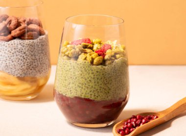 Red Bean Matcha Soya Milk Chia Pudding with Granola and Dried Berries in g;ass side view of healthy breakfast