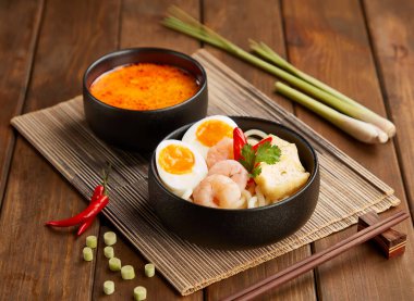 Baharatlı Udon Eriştesi. Zengin Laksa Çorbası, tofu pufları, taze biber ve Asya mutfağı manzaralı haşlanmış yumurta.