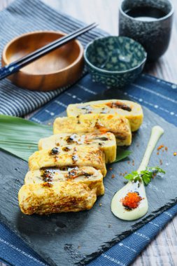 Izgara yılan balığı ve Tamagoyaki krema soslu Japon usulü omlet ve ana yemek tabağında servis ediliyor.