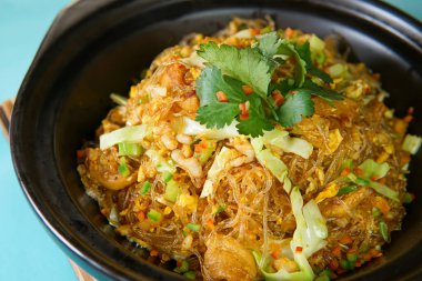 Kızarmış vermicelli şehriyeli soslu domuz pastırması ve yabani sebzeler Asya mutfağına yakın bir Clay Pot görüntüsü.