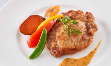 Hokkaido Izgara Domuz Pirzolası ve Paris usulü Kızarmış Sebze ve Sosla Restoran menülerinin yakın plan beyaz tabağında