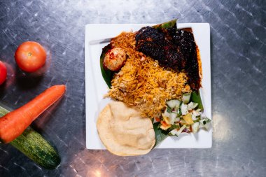 Baharatlı Balık Biryani, yumurta, salata ve beyaz tabakta yan yemekler Hint baharatının arka planında izole edilmiş.