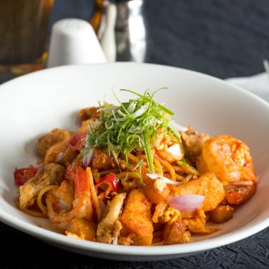 Baharatlı deniz ürünleri spagettisi Mee Goreng, karides, balık keki ve karides kasesinde Asya yemeğinin yan görüntüsü.