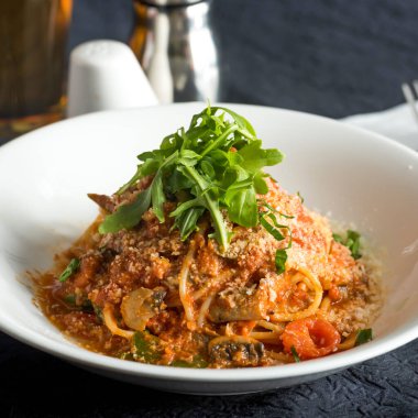 Taze Arugula ve Parmesan peynirli spagetti ile nefis Caprese Makarnası. Domates soslu ve mantarlı İtalyan yemeğinin yakın görüntüsü.
