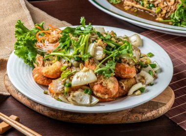 Soğanlı çıtır biberli karides, sarımsak ve beyaz tabakta taze garnitür, yakın çekim kenarı manzarası.