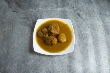 Beyaz tabakta servis edilen baharatlı soslu haşlanmış yumurtalı geleneksel tavuk köri.