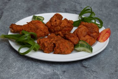 Baharatlı Tayland usulü kızarmış tavuk. Soğan ve salatalık dilimleri tabakta.