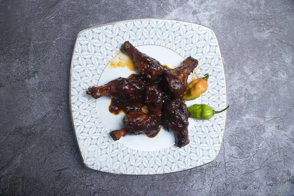 Yapışkan BBQ Tavuk Davul Çubuğu Lolipopları. Atıştırmalık tabağında acı biber var.