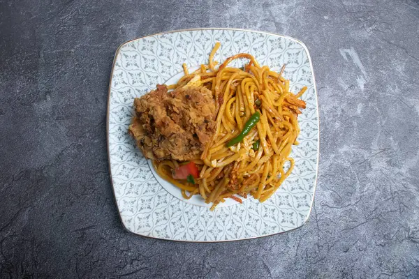 Sebzeli erişte ve bir parça kızarmış tavuk. Asya yemeklerinin üst tabaklarında.