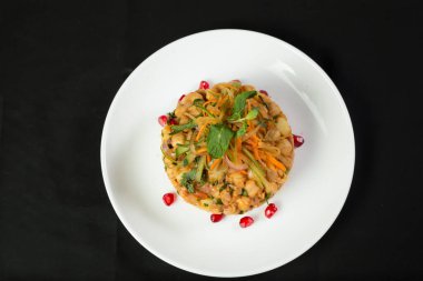 Baharatlı Chana Chaat soğanlı, domatesli, havuçlu, salatalıklı ve nar tohumlu koyu arkaplanlı Hint nohut salatası.