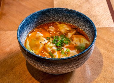 Kırmızı biber soslu baharatlı Sichuan Wontonu ve ana yemek tahtasının yanında susam tohumu ve scallion çorbası.