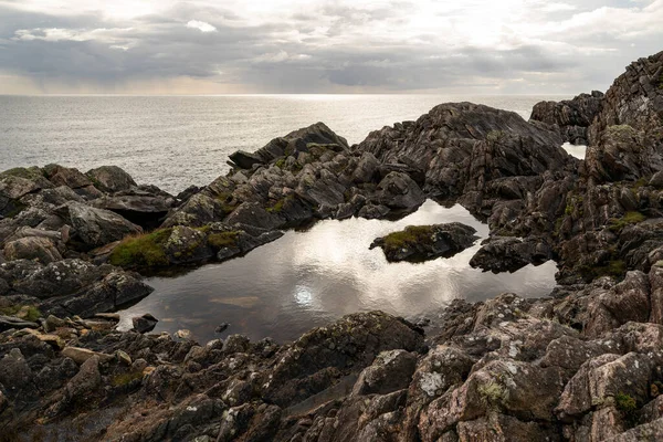 Dramatic sky reflected in a rock pool at Annagh Head, Mullet peninsula, County Mayo, Ireland