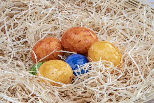 Colorful painted Easter eggs hidden in straw for an Easter egg hunt.