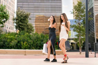 Alışveriş torbalarıyla gezen ve şehirde yeni mallar almak için kahve içen bir sürü genç kız arkadaş.