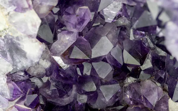 Keskin ve canlı mor ametist kristal kümelerini doğal geometrik yüzeylerle gösteren detaylı makro yakın çekim fotoğrafı