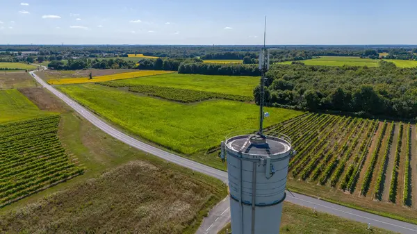 stock image Water Tower with 5G Antenna Overlooking Vineyards and Rural Roads