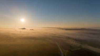 Serene Sunrise Over Foggy Farmland with Soft Golden Light clipart