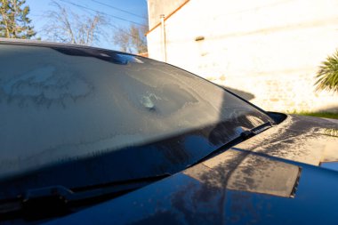 Frost-covered car windshield on a sunny morning. clipart