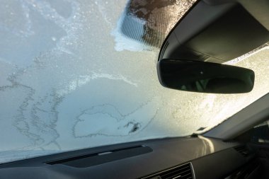 Frosted car windshield from interior view with sunlight. clipart