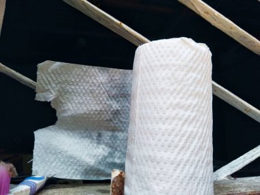  Görüntü, arkasında kısmen kullanılmış tuvalet kağıdı olan beyaz bir tuvalet kağıdı rulosunu gösteriyor..