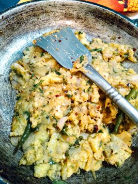  Görüntü, içinde spatula olan bir yemek kalıbını gösteriyor. Yemekler sebze ve yumurta karışımı gibi görünüyor..