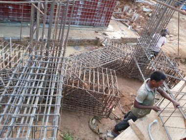 25 Temmuz 2024 Dhaka, Bangladeş. Görüntü işçilerin, ekipmanların ve malzemelerin bulunduğu bir inşaat alanını gösteriyor. İşçiler ayakta kalıp malzemelerle çalışıyorlar.. 