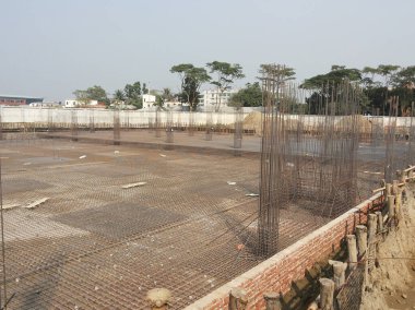 31 Temmuz 2024 Dhaka, Bangladeş. Bu görüntü kısmen bitmiş tuğla bir duvar ve tel örgülü bir inşaat alanını gösteriyor. Gökyüzü kapalı..