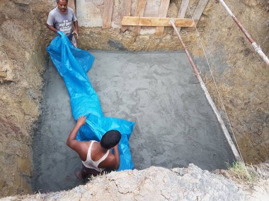 3 Temmuz 2024 Dhaka, Bangladeş. Görüntü, çimento kalıbına beton döken iki adamı gösteriyor..