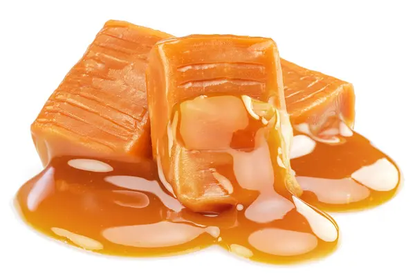 Beyaz arkaplanda izole edilmiş erimiş karamel kaplı süt karamel şekerleri.