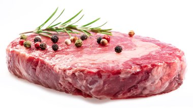 Raw ribeye steak with peppercorn and rosemary isolated on white background. Closeup. 