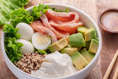 Ahşap masada sebzeli somon kinoa kasesi. Kasedeki denge. Üst görünüm.