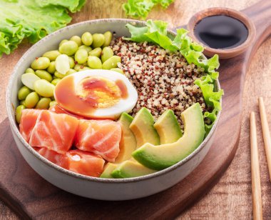 Sebze ve sebzeli somon kinoa kasesi ahşap masada denge kasesi. Üst görünüm.