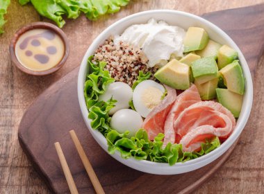 Ahşap masada sebzeli somon kinoa kasesi. Kasedeki denge. Üst görünüm.