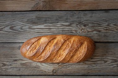 Ahşap arka planda taze pişmiş ekmek. Geleneksel taze ekmek, uzun rulo şeklinde..