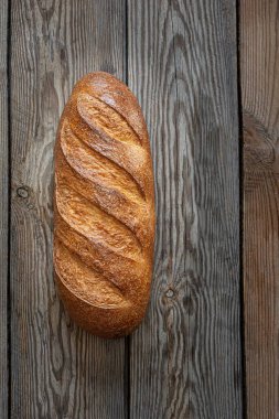 Ahşap arka planda taze pişmiş ekmek. Geleneksel taze ekmek, uzun rulo şeklinde..