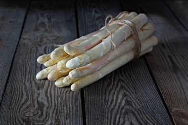 Fresh white asparagus on a wooden background. Photo in low key. Raw food concept.