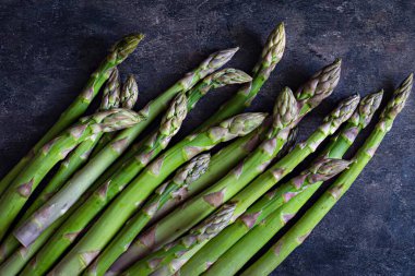 Green asparagus on a dark background. Raw food concept. The vegetable is rich in fiber, a natural prebiotic.