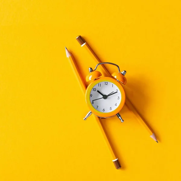 stock image Orange alarm clock with pencils on orange background. The concept of awakening, work time, training (studying), back to school. Get up, wake up and live, business deadline, copy space. Time is money.