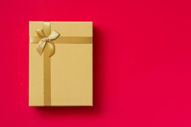 Altın (sarı) kutu, kırmızı arka planda hediye. Doğum günü, Noel, Sevgililer Günü, Anneler Günü konsepti.
