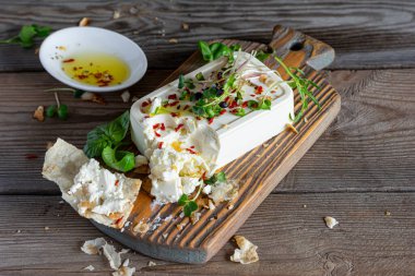 Tahta bir tahta üzerinde zeytin, bitki, baharat ve bir dilim düz ekmek (tortilla, lavaş, pitta, chapatti) ile bir parça taze peynir (paneer) ve koyu bir arka plan. Yunan mutfağı, sağlıklı yemekler..