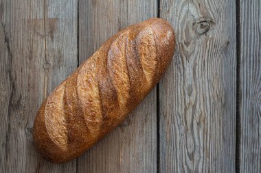 Ahşap arka planda taze pişmiş ekmek. Geleneksel taze ekmek, uzun rulo şeklinde..